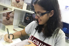 Jéssica Sanz, do 8º período do Curso de Licenciatura em Letras,  autografa exemplar de seu 3º  livro (Foto: Divulgação)