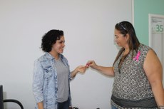 Paula Bastos entrega laço de fita da Campanha Outubro Rosa à servidora da Reitoria
